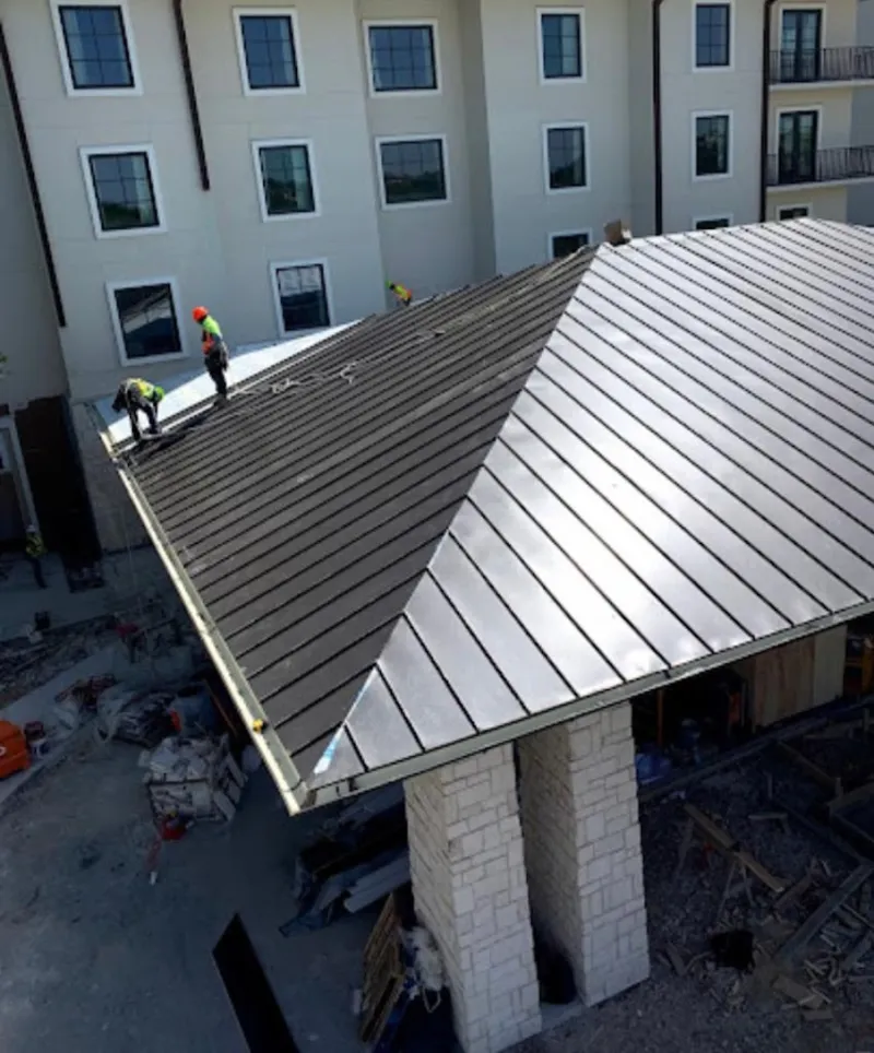 Crew installing standing seam metal roof panels on a commercial project in Lumberton
